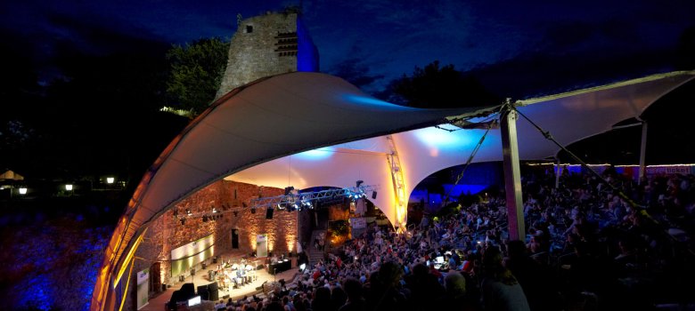 WDR5 Literarische Sommernacht 2012 Blick auf eine Freilichtbühne mit vollen Zuschauerrängen am Abend.