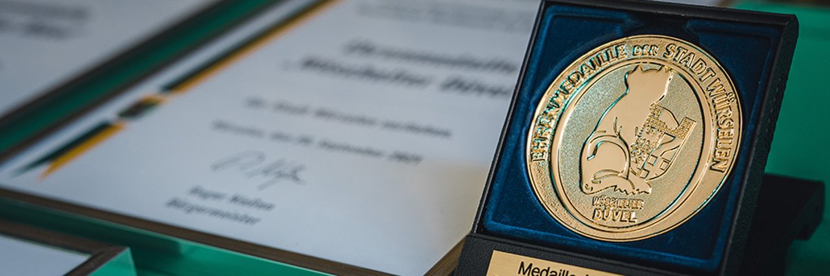 Ehrenmedaille Goldene Medaille auf der ein Teufel abgebildet ist.