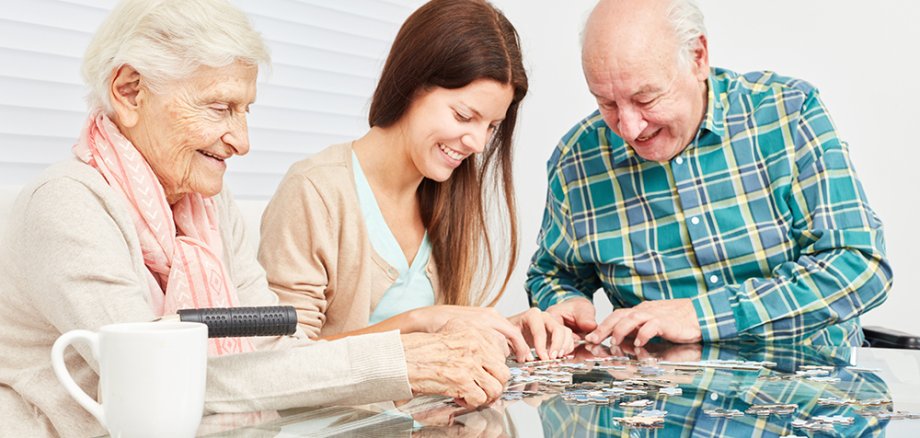 Familie mit Enkeltochter und Senioren spielen Puzzle als Gedächtnistraining