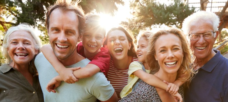 Outdoor Portrait Of Multi-Generation Family Walking In Countryside Against Flaring Sun Familie, die sich umarmt