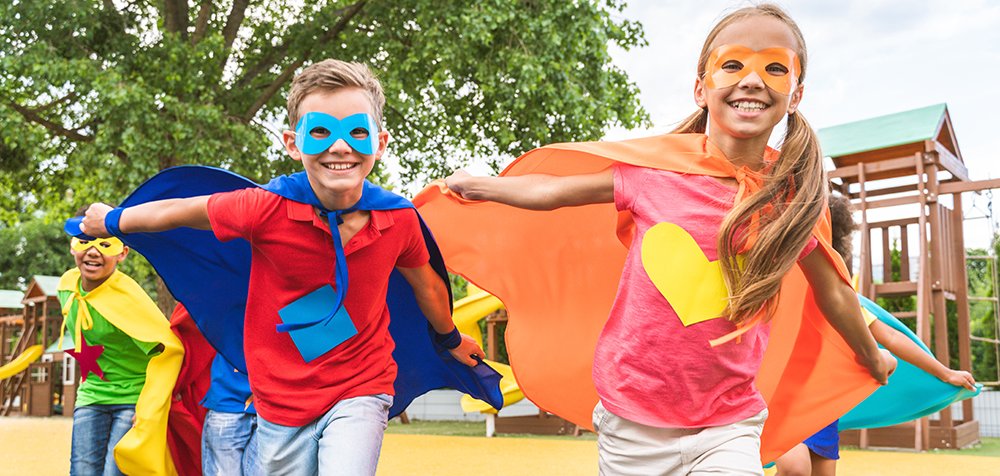Kinder verkleidet als Superhelden laufen auf dem Spielplatz.