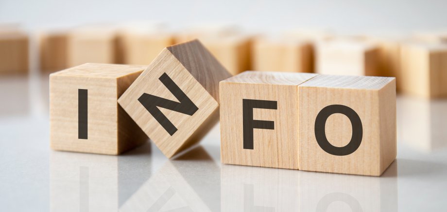 four wooden blocks with the letters info on the bright surface of a gray table, business concept Vier Würfel mit den Buchstaben I N F O