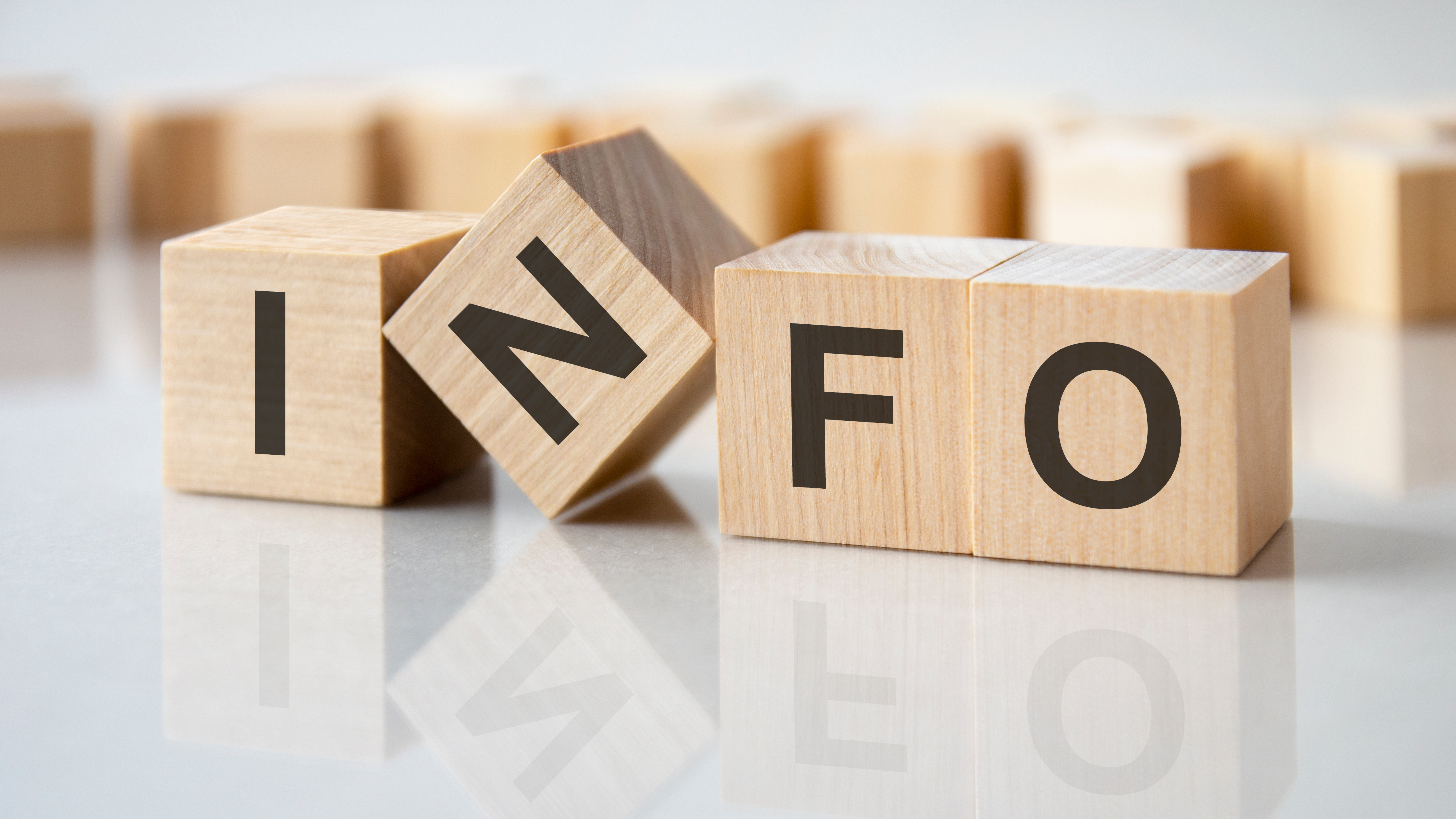 four wooden blocks with the letters info on the bright surface of a gray table, business concept Vier Würfel mit den Buchstaben I N F O