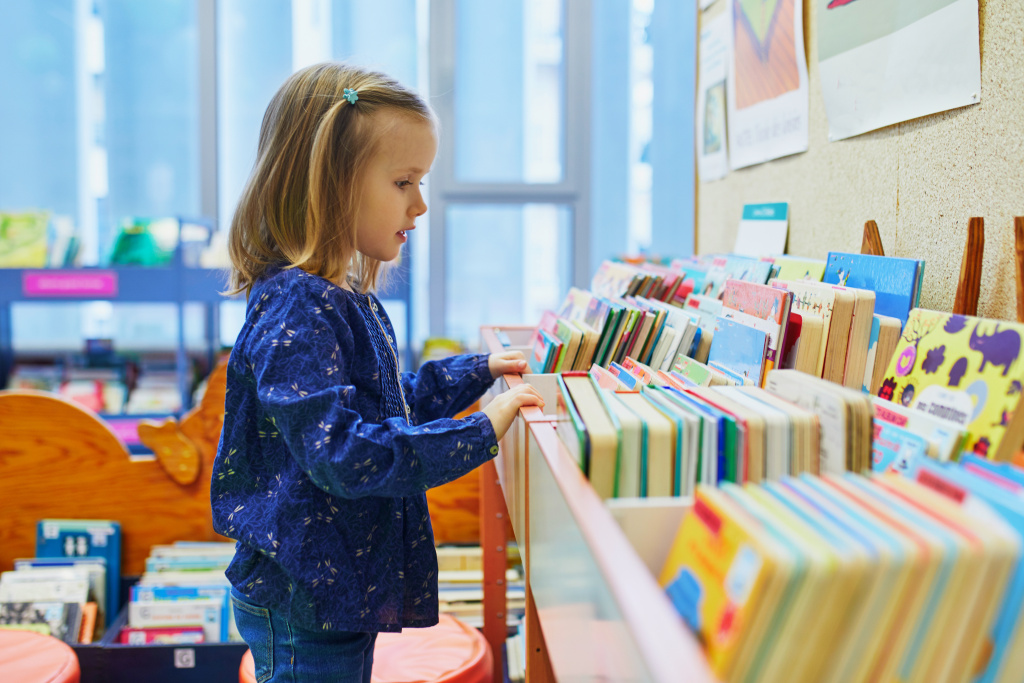 Mädchen steht am Bücherregal.