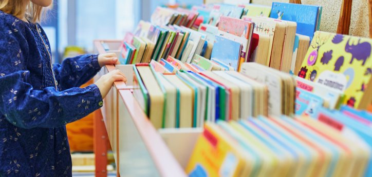 Mädchen steht am Bücherregal.