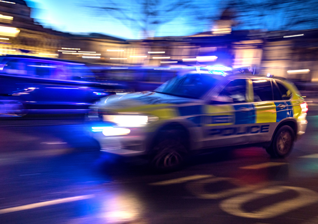 Ein Polizeiauto mit Blaulicht fährt schnell über die Straße.