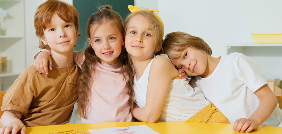 Vier kinder umarmen sich und schauen dabei in die Kamera.