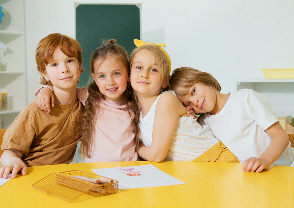 Vier kinder umarmen sich und schauen dabei in die Kamera.