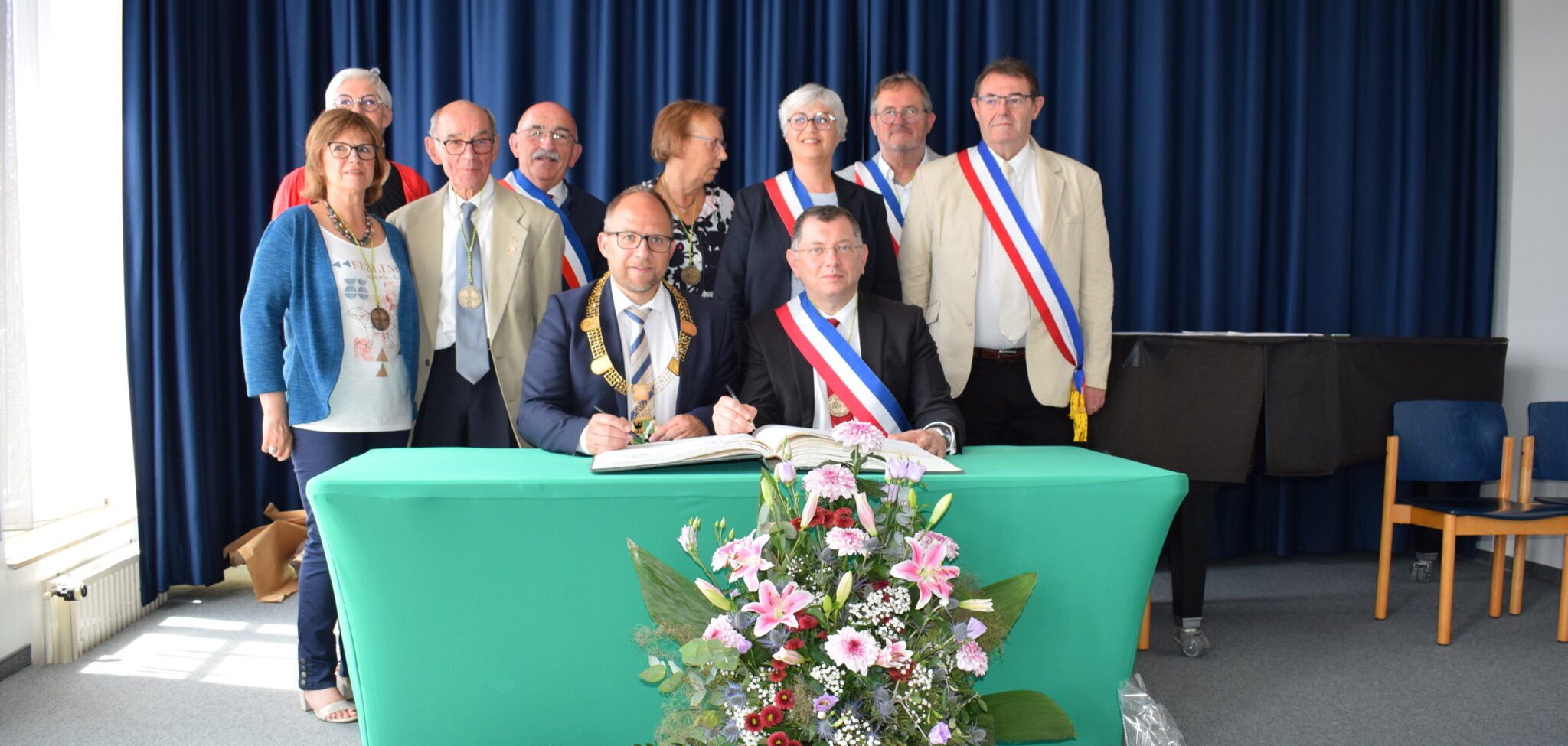 Mehrer Leute hinter einem Tisch beim Eintrag ins Goldene Buch