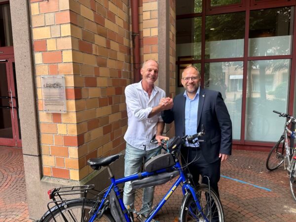 Albert Küppenbender radelt für den guten Zweck Zwei Männer vor dem Rathaus mit einem Fahrrad