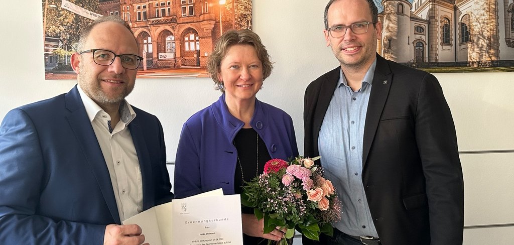 Heike Ohlmann mit Bürgermeister Roger Nießen und Kämmerer Alexander Kaiser. Sie hält einen Blumenstrauß.