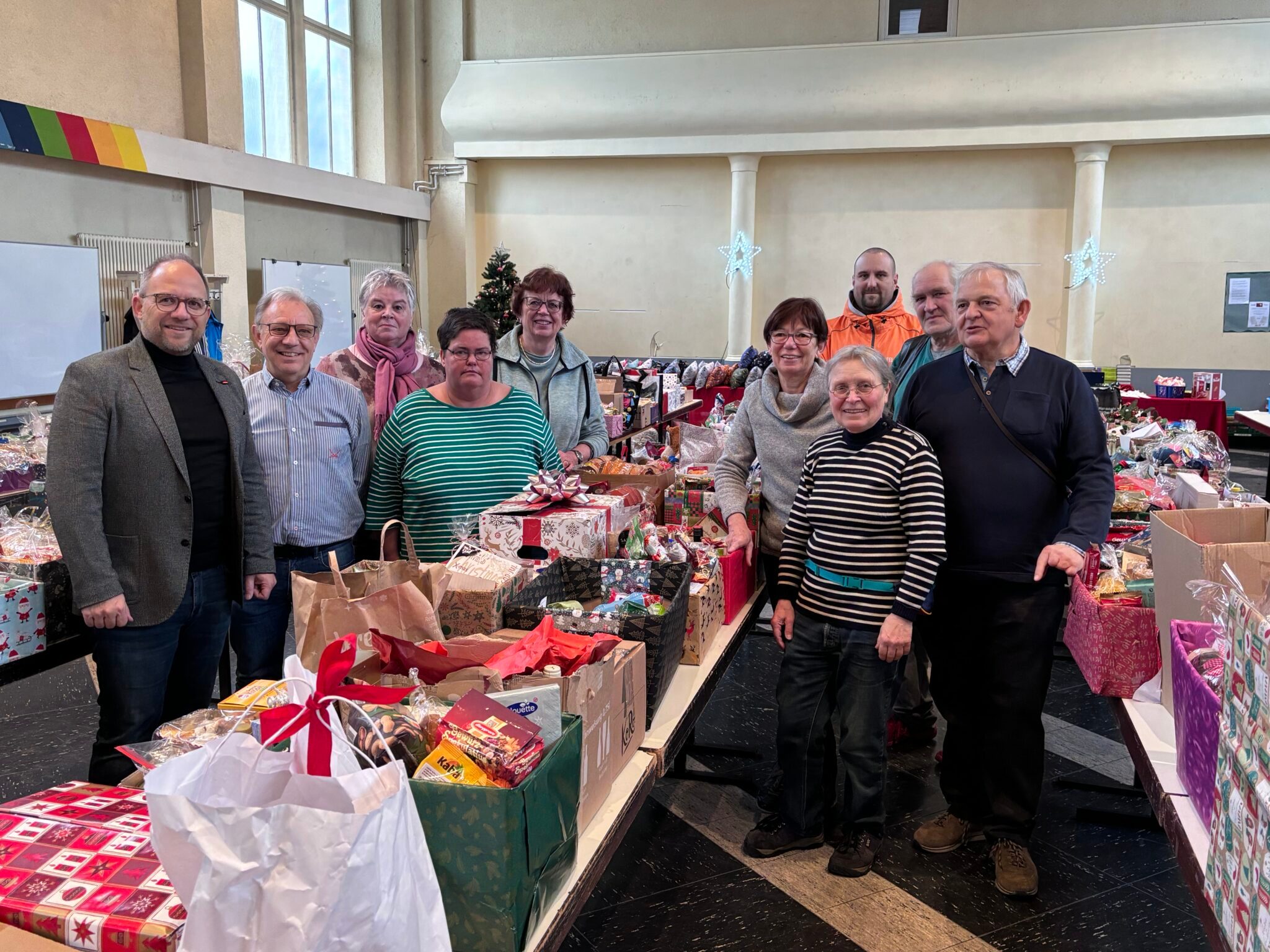 Tische mit Weihnachtspaketen und mehreren Leuten.