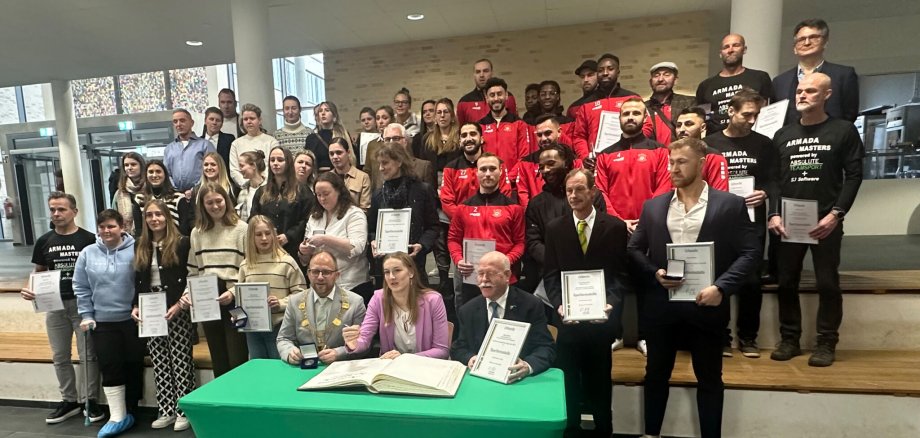 Viele Sportler hinter einem Tisch mit dem Goldenen Buch Stadt Würselen und Bürgermeister Nießen