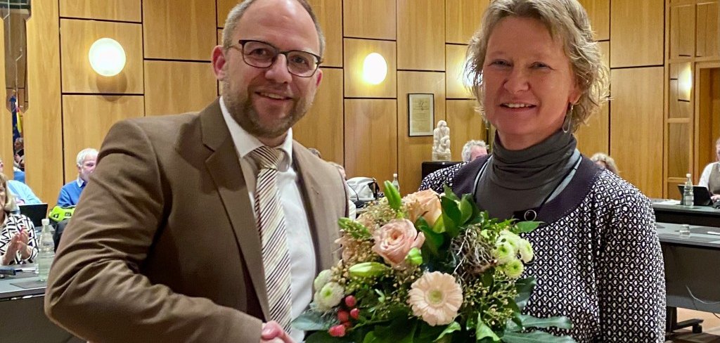Bürgermeister Nießen überreicht einen Blumenstrauß und gratuliert Heike Ohlmann.