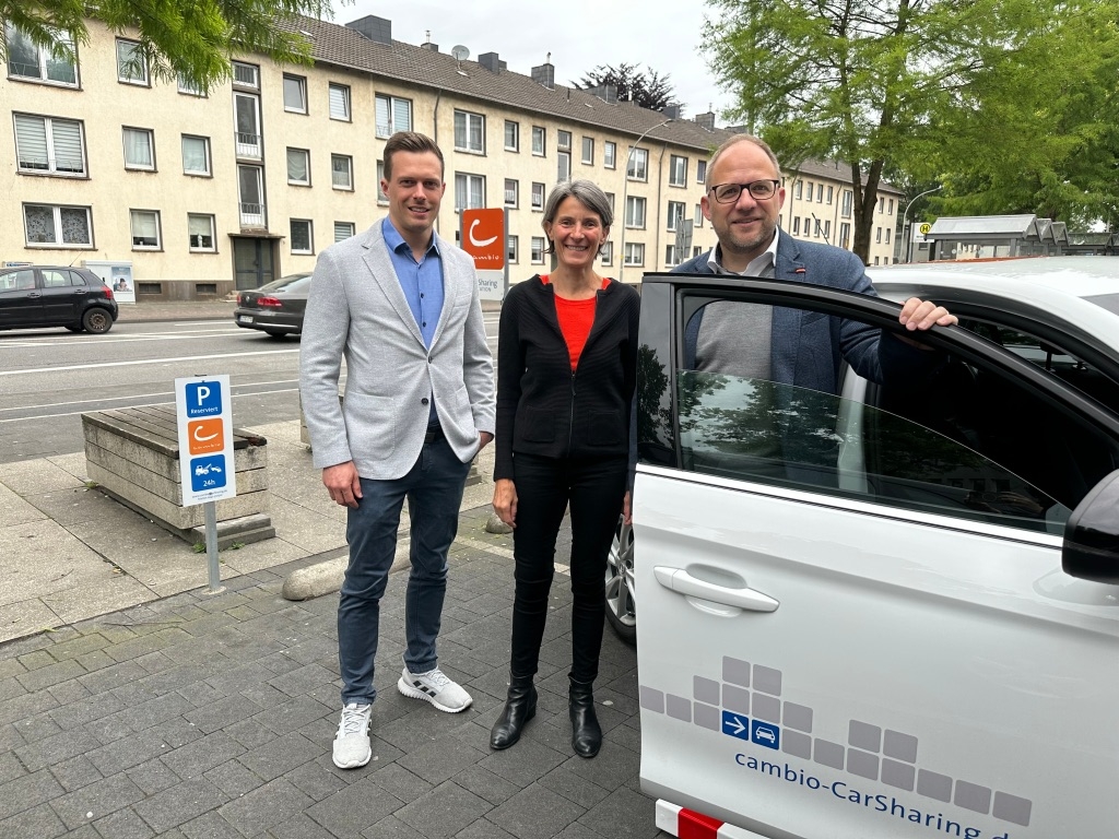 Bürgermeister Roger Nießen und Planungsamtsleiter Benjamin Gard stehen an einem Cambio Auto auf einem Cambio Stellplatz.