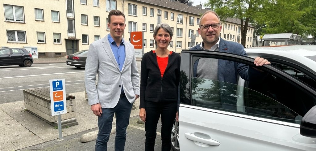 Bürgermeister Roger Nießen und Planungsamtsleiter Benjamin Gard stehen an einem Cambio Auto auf einem Cambio Stellplatz.