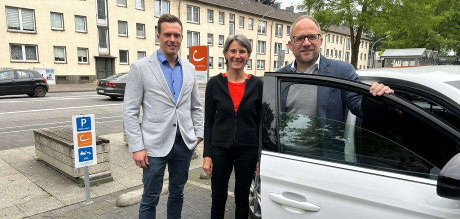 Bürgermeister Roger Nießen und Planungsamtsleiter Benjamin Gard stehen an einem Cambio Auto auf einem Cambio Stellplatz.