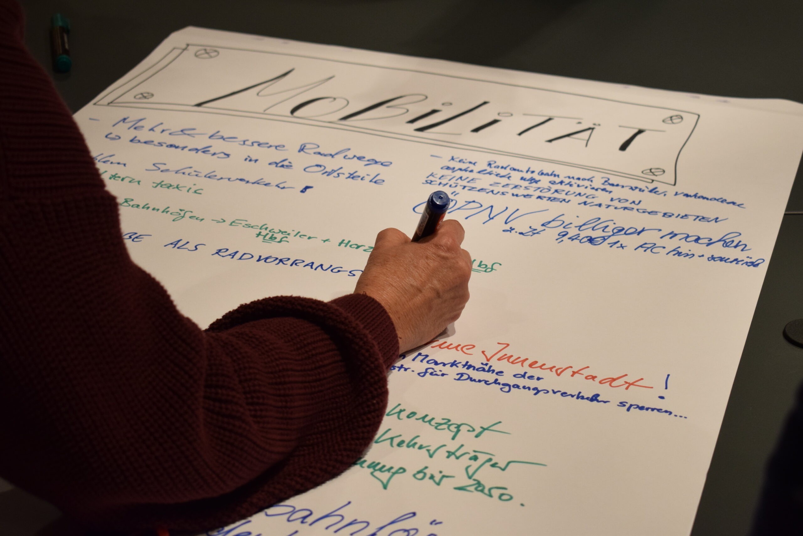 Eine Person schreibt mit einem Stift auf ein großes Plakat.