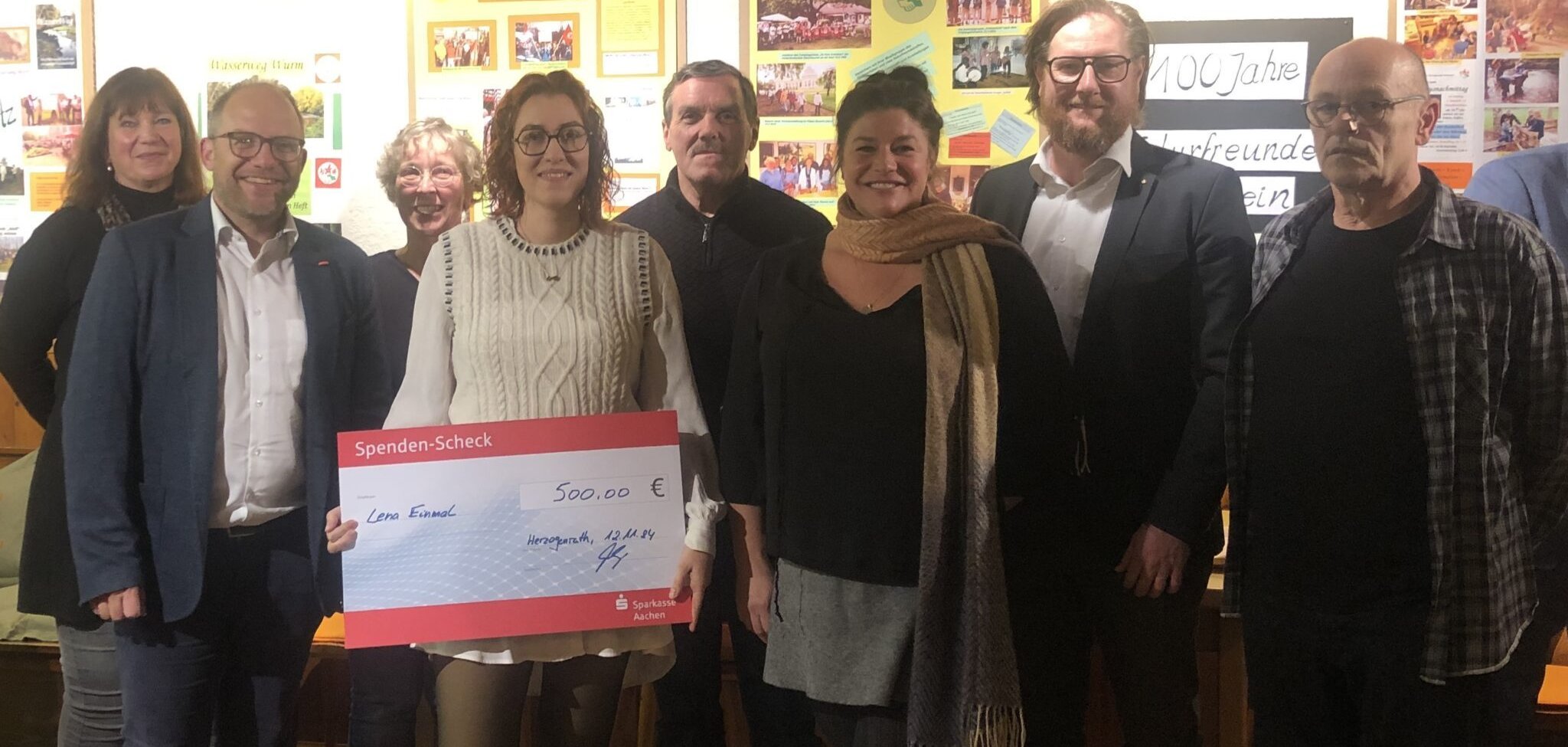 Mehrer Leute mit Siegerin die einen Scheck hält