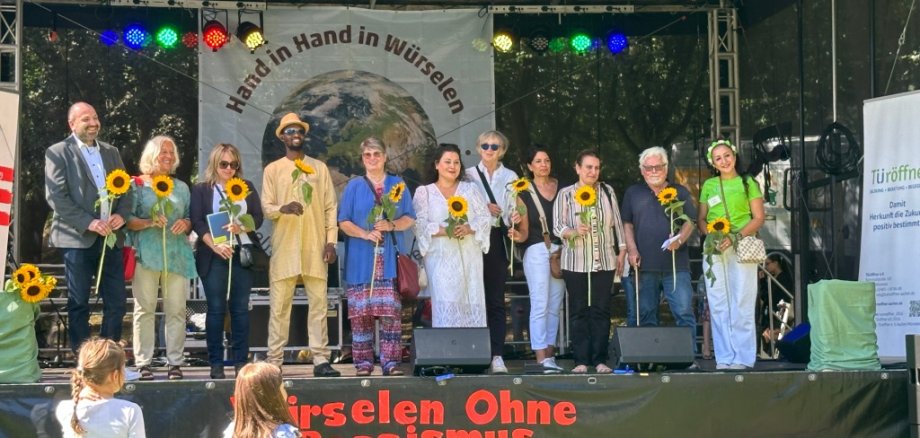 Bühne mit vielen Menschen, die eine Sonnenblume halten.