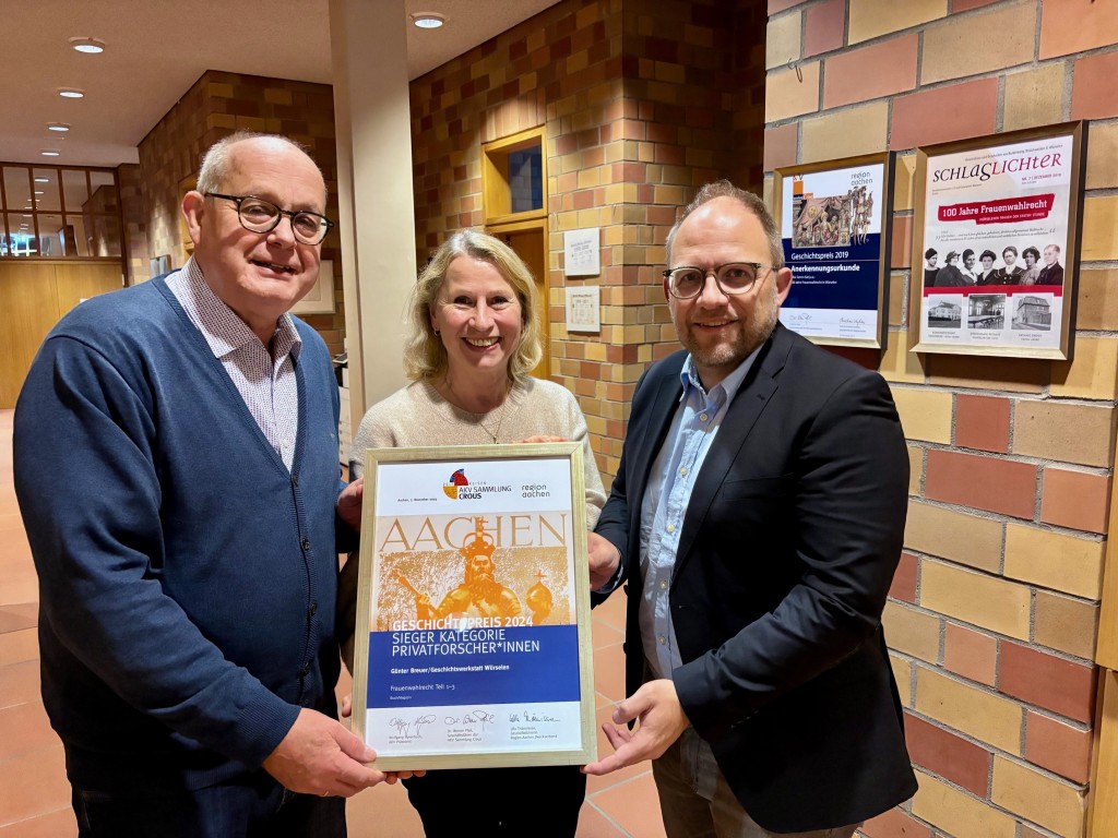 Eine Frau hält eine Urkunde fest, links und rechts neben ihr steht jeweils ein Mann: Gleichstellungsbeauftragte Silke Tamm-Kanj mit Bürgermeister Roger Nießen und Günter Breuer