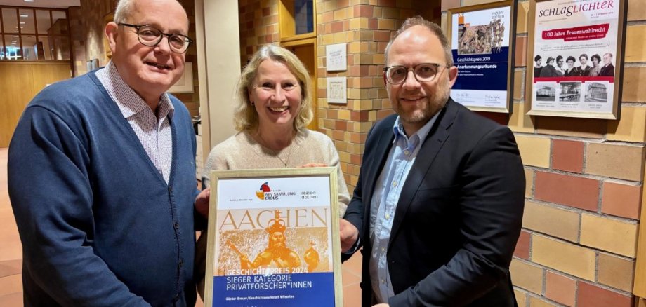 Eine Frau hält eine Urkunde fest, links und rechts neben ihr steht jeweils ein Mann: Gleichstellungsbeauftragte Silke Tamm-Kanj mit Bürgermeister Roger Nießen und Günter Breuer
