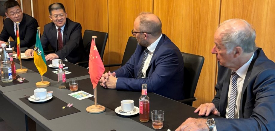 Vier Männer sitzen an einem Tisch und unterhalten sich.