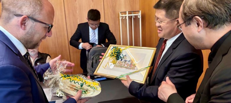 Drei Herren überreichen sich Gastgeschenke.
