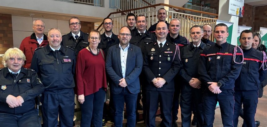 Eine Gruppe Menschen steht im Foyer des Rathauses, darunter einige Feuerwehrleute.