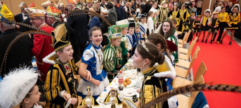 VIele Kinder in Karnevalsuniformen sitzen an einem Tisch
