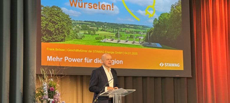 Ein Mann steht an einem Rednerpult auf einer Bühne und hält einen Vortrag.