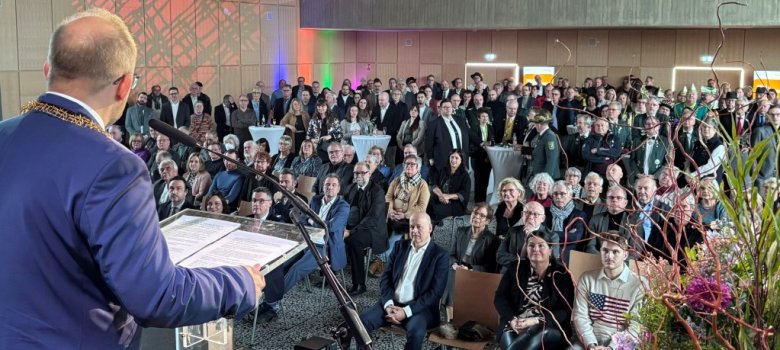 Der Bürgermeister steht auf der Bühne und spricht zu den zahlreichen Leuten im Publikum