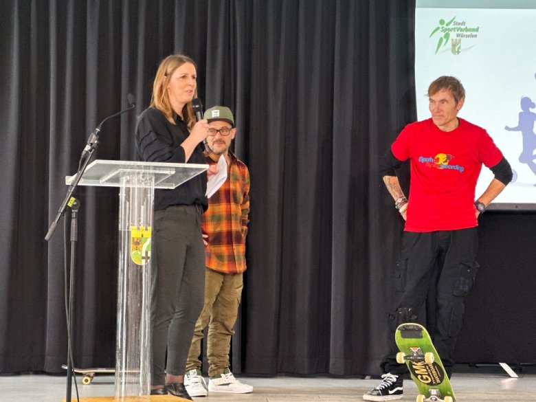 Auf der Bühne begrüßt Pressesprecherin Miriam Ameri den Skateboard-Freestyler Guenter Mokulys und Oliver aus dessen Team, der die Stunts kurz erklärte.