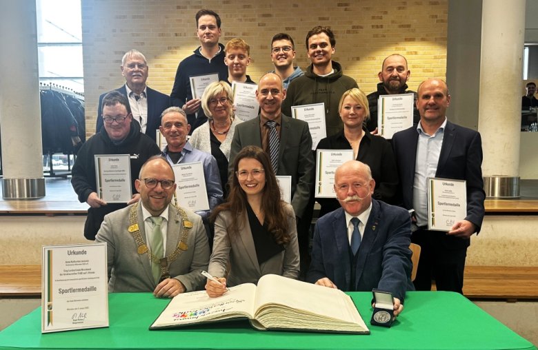 Die geehrten Sportler:innen und Ehrenamtlichen tragen sich gemeinsam mit Bürgermeister Roger Nießen und Hans-Josef Bülles vom Stadtsportverband in das Goldene Buch der Stadt Würselen ein.