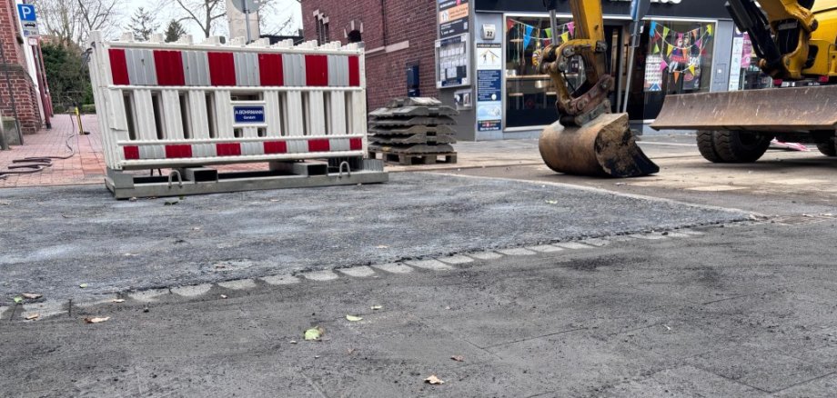 Ein Bagger und Absperrgitter auf einer Straße.