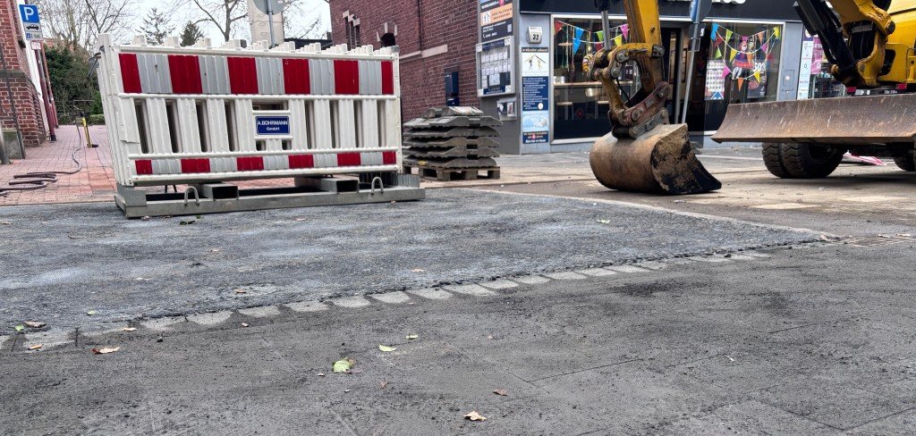 Baustelle Kaiserstraße Ein Bagger und Absperrgitter auf einer Straße.