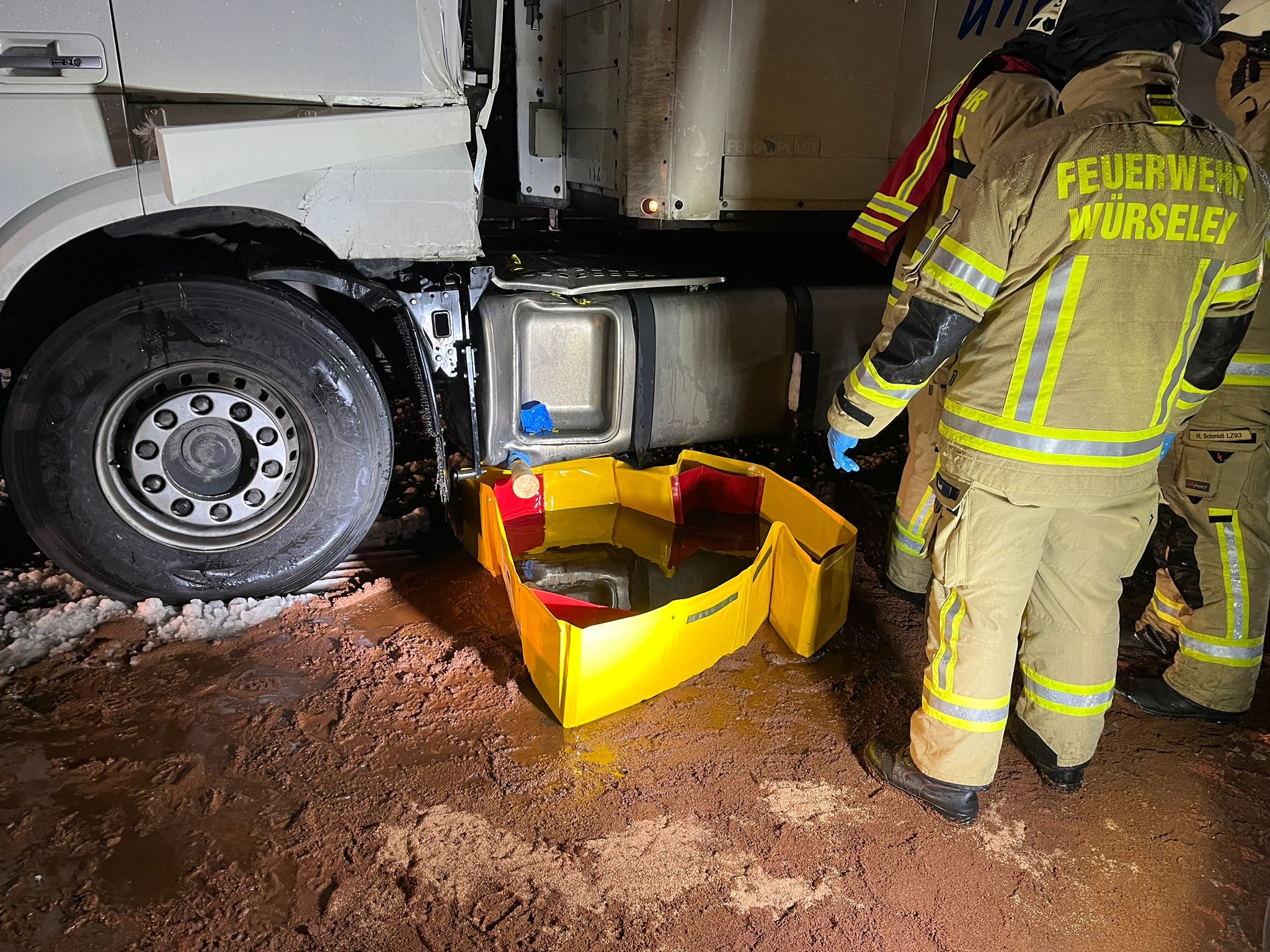 Beschädigter LKW nach Unfall mit einer Auffangschale für Benzin und 3 Feuerwehrleute