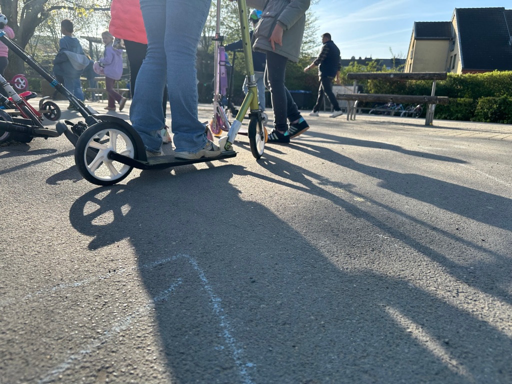Kinder mit Rollern und Helm.