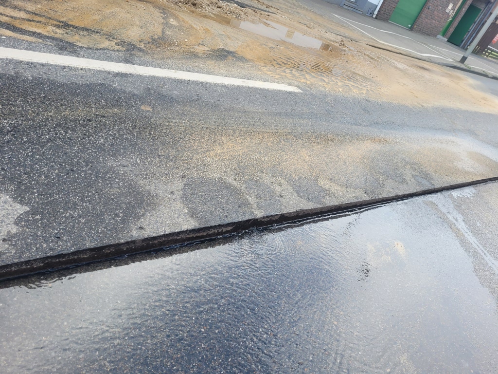 Die Fahrbahndecke ist gespalten, Wasser sickert ein.