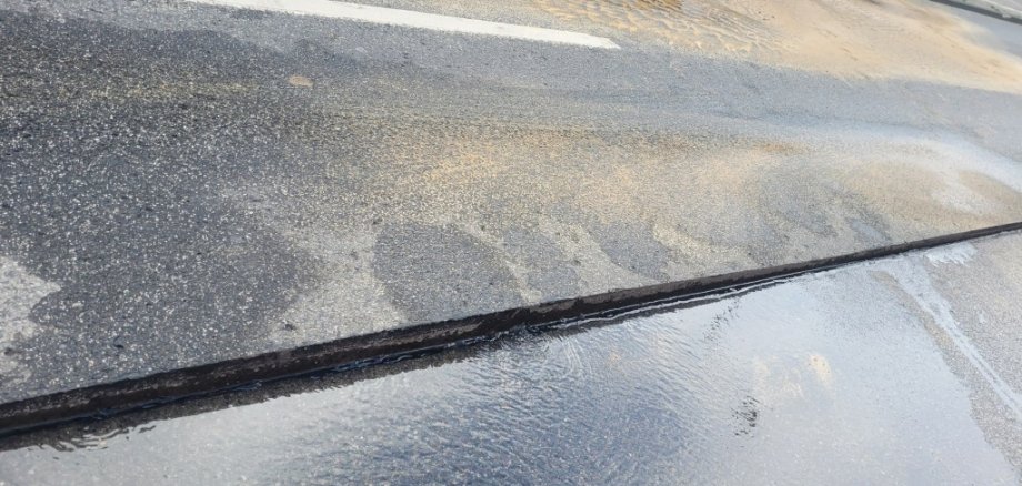 Die Fahrbahndecke ist gespalten, Wasser sickert ein.