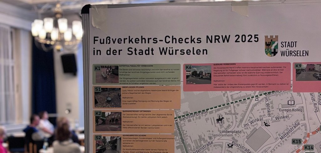 Eine Straßenkarte an einer Pinnwand in einem Saal mit Menschen