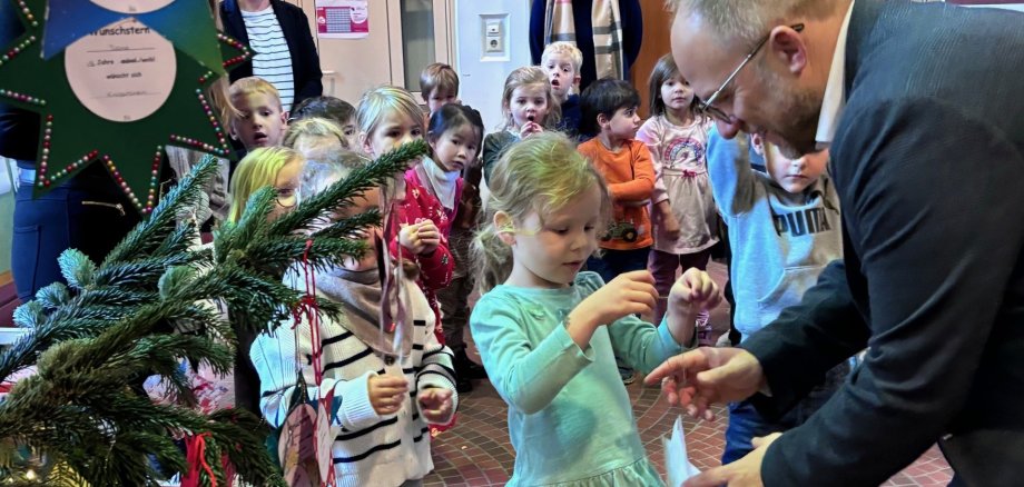 Bürgermeister Roger Nießen schmückt mit den Kindern den Baum.