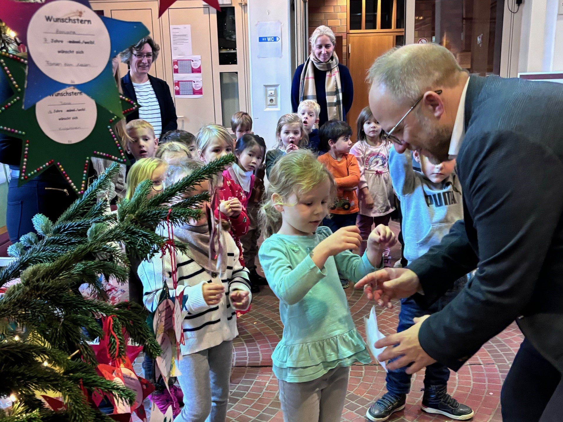 Bürgermeister Roger Nießen schmückt mit den Kindern den Baum.