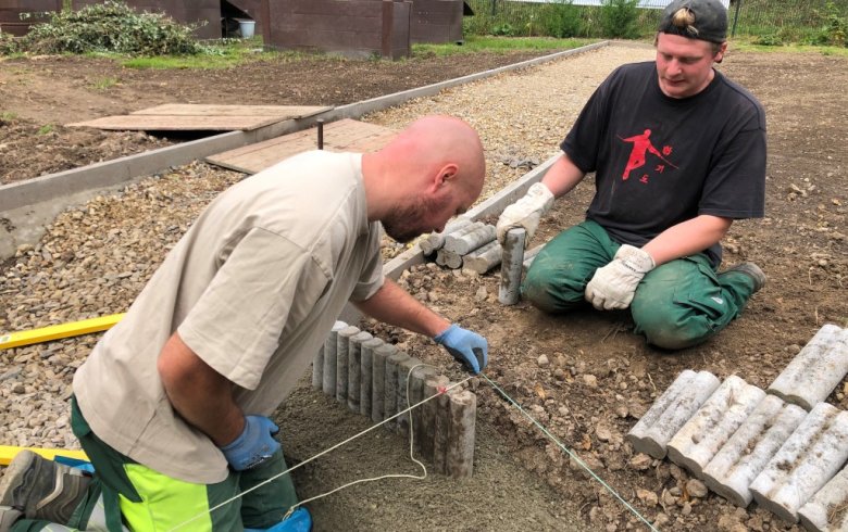 Präzise Arbeit ist bei der Anlage des zentralen Rondells gefragt: Gruppenleiter Oliver Rohner (links) und Tim Wüller arbeiten gemeinsam an der äußeren Randeinfassung.