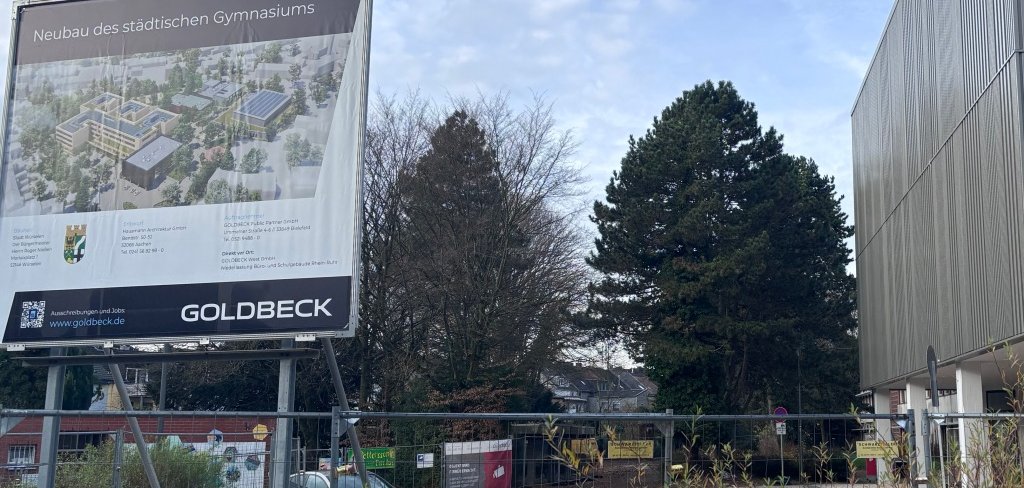 Baustellenschild Gymnasium Baustellenschild mit Informationen zum Neubau des Gymnasiums, im Hintergrund die Aula/Stadthalle und Teile des alten Gebäudekomplexes