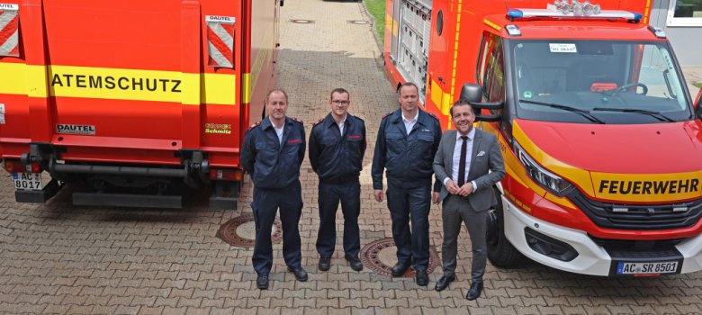 Vier Personen zwischen Feuerwehrautos